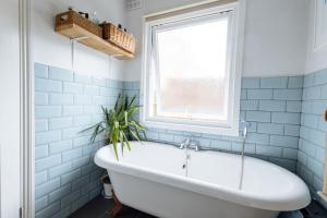 łazienka z wanną i oknem w obiekcie Unique private apartment w/ Easy access to Central London w Londynie