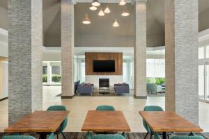 um átrio com mesas e cadeiras e uma lareira em Hilton Garden Inn Houston Energy Corridor em Houston