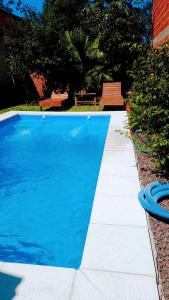 una piscina azul con un banco en un patio en Lo De Grace -Casa vacacional en Puerto Iguazú