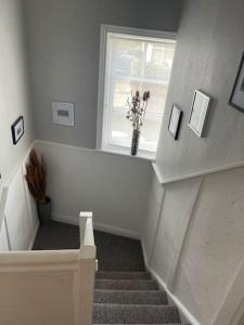 a staircase with a window and a vase with flowers in it at Rooms@ Remedy 2 bedroom (sleeps 5) apartment in Crossens