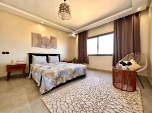 a bedroom with a bed and a chair and a window at Moderne, lumineux & spacieux avec balcon -Central -Wifi-Smart TV-Clim in Marrakesh