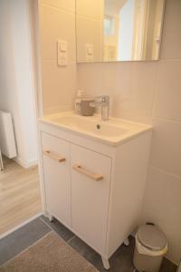 a white bathroom with a sink and a mirror at Le Marais - Appart'Escale in Saint-Nazaire