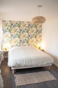 a bed in a bedroom with a floral wall at Le Marais - Appart'Escale in Saint-Nazaire