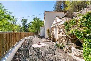 eine Terrasse mit einem Tisch, Stühlen und einem Zaun in der Unterkunft Molino del Nacimiento in Laujar de Andarax