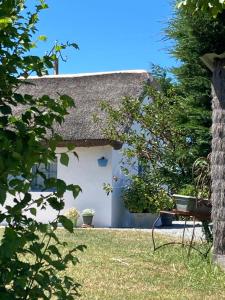 um pequeno chalé branco com um telhado de palha em Les Pensions du Joslin em Bouin