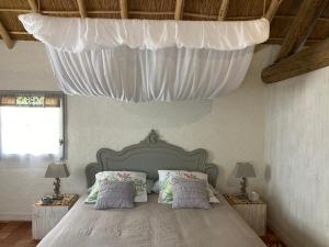 een slaapkamer met een groot bed met een witte baldakijn bij Les Pensions du Joslin in Bouin