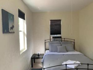 a bedroom with a bed and a table and two windows at Private Rooms close to Miami Airport - Free parking - 02 in Miami