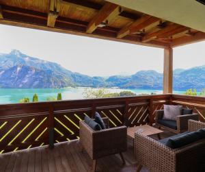 a deck with chairs and a table and a view of a lake at Naturtalente Berghaus - Moonlakeview Big in Innerschwand am Mondsee