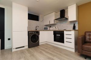 a kitchen with white cabinets and a washer at The Oasis Apartment in Leeds