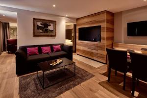 a living room with a black couch and pink pillows at Staufen Chalets am Kalvarienberg in Oberstaufen