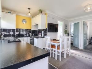 a kitchen with white cabinets and a table and chairs at Resthaven in Harwich
