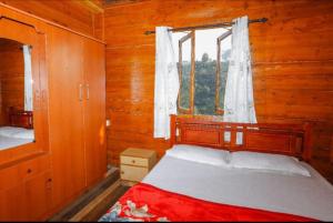 una camera con letto e finestra in una baita di tronchi di Sandy Wood House Ooty - 2Bhk Villa a Ooty