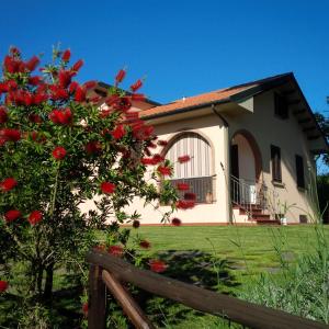 a house with red flowers in front of a fence at Campo del Rosario in Montescudaio