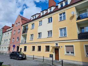 un edificio amarillo con un coche aparcado delante de él en Apartament in Centre 2 en Bolesławiec