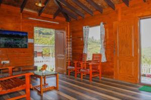 un soggiorno con sedie, tavolo e finestre di Sandy Wood House Ooty - 2Bhk Villa a Ooty