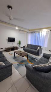 uma sala de estar com sofás, uma mesa e uma televisão em Crystal beach apartment em Mombasa