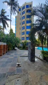 um edifício com palmeiras em frente a uma piscina em Crystal beach apartment em Mombasa