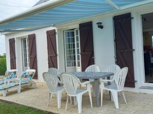 a table and chairs on a patio with a blue awning at maison de l ile in Damgan