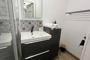 La salle de bains est pourvue d'un lavabo blanc et d'une douche. dans l'établissement L'échappée MERs- Maison 3 chambres au Centre 500m de la plage, à Mers-les-Bains