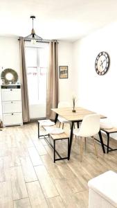 une salle à manger avec une table, des chaises et une horloge dans l'établissement L'échappée MERs- Maison 3 chambres au Centre 500m de la plage, à Mers-les-Bains