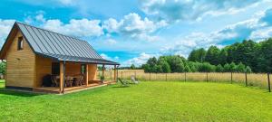 a small house with a roof on a grass field at Domek letniskowy Wigsun in Leszczewek