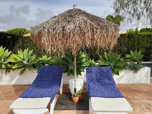 two blue and white chairs and a straw umbrella at casita en la playa in El Rompido