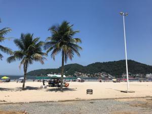 a beach with palm trees and people on the beach at Kit pé na areia - Praia do Gonzaguinha - São Vicente - Wi-Fi e Estacionamento in São Vicente