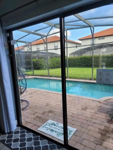 a view of a swimming pool through a glass door at Luxry villa 6 miles from Disney in Orlando