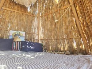 1 dormitorio con 1 cama en una pared de paja en Cosmos Camp, en Dahab