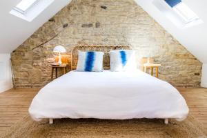 ein Schlafzimmer mit einem großen weißen Bett mit blauen Kissen in der Unterkunft Mer nature, appartement spacieux by Les Filles du Bord de Mer, petite terrasse vue mer in Port-en-Bessin-Huppain