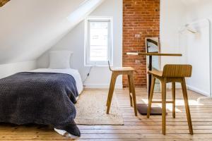 ein Schlafzimmer mit einem Bett, einem Stuhl und einer Ziegelwand in der Unterkunft Mer nature, appartement spacieux by Les Filles du Bord de Mer, petite terrasse vue mer in Port-en-Bessin-Huppain