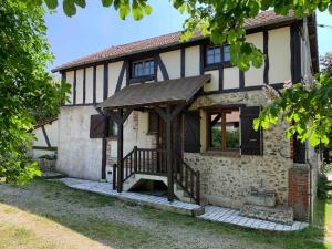 een oud huis met een houten prieel bij Maison de famille au vert classée 3 étoiles in Les Andelys