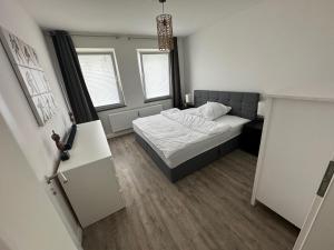 a small bedroom with a bed and two windows at Seibels SUITES - Wohnung Ruhrgebiet in Herne