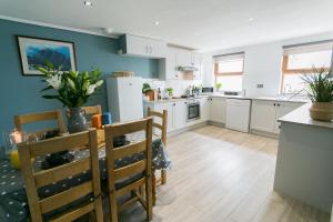 a kitchen with white cabinets and a table and chairs at Tan y Bryn Bach in Llanllechid