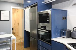a kitchen with a microwave and a blue wall at Duplex Ávila in Ávila