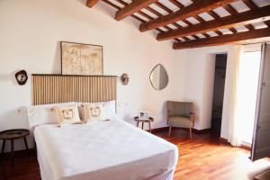1 dormitorio con 1 cama blanca y 1 silla en Hotel Palou 1874, en Sant Pere de Ribes