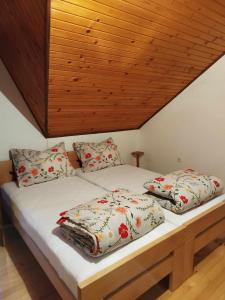 łóżko z poduszkami i drewnianym sufitem w obiekcie Prenoćište Rubin 
