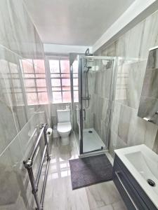 a bathroom with a shower and a toilet and a sink at Vibrant 2-Bedroom Flat with Elevator in Marylebone, Close to Hyde Park & Edgware Road in London