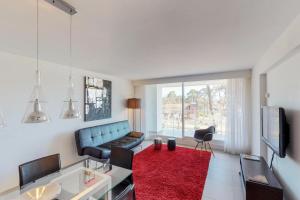 - un salon avec un canapé bleu et un tapis rouge dans l'établissement Oceana Suites en Yoo, con piscina interior climatizada, à Punta del Este