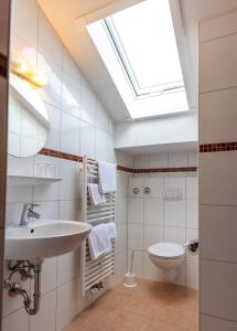 bagno con lavandino, servizi igienici e lucernario. di Hotel Alpenhof a Oberau