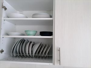 a white cabinet with plates and bowls on it at JOY's Central Apartment in Thessaloniki