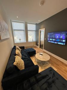 a living room with a black couch and a tv at Hamlet Court Apartments 1A in Southend-on-Sea