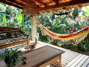 a porch with a hammock and a bench and flowers at Casa da Ilha Paraty Entre a mata atlântica e o mar in Paraty