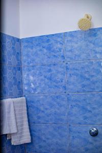 a blue tiled bathroom with a shower with a towel at Kilifornia Comfy Studio in Kilifi