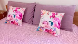3 Kissen auf einem Bett mit rosa Blumen in der Unterkunft La Rocconella in Arten