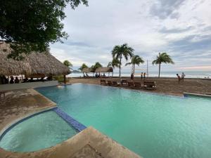 una piscina junto a una playa con palmeras en Iguana budged room Stop N Go Surf, en Tola