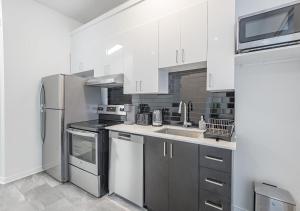 uma cozinha com armários brancos e um frigorífico de aço inoxidável em Luxurious 3BD Apt in heart of downtown Free Parking on-site 5 min walk to Bell Center em Montreal