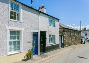 a white house with a blue door on a street at 10 Beach Road in Menai Bridge