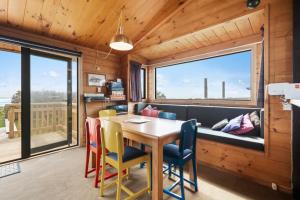 een eetkamer met een tafel en stoelen en een groot raam bij The Beachsider - Te Horo Beach Holiday Home in Te Horo