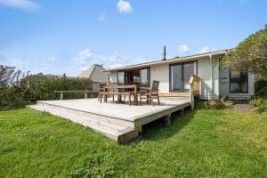 a wooden deck with a table and chairs on a house at The Beachsider - Te Horo Beach Holiday Home in Te Horo